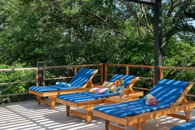 a deck with two lounge chairs and a table at Casa Mimosa in Playa Flamingo