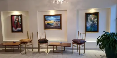 a group of tables and chairs in a room with paintings at LOP Inn San Jose Aeropuerto - Costa Rica in Ciudad Cariari