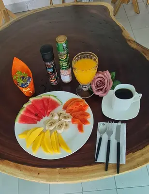 a table with a plate of fruit and a cup of coffee at LOP Inn San Jose Aeropuerto - Costa Rica in Ciudad Cariari
