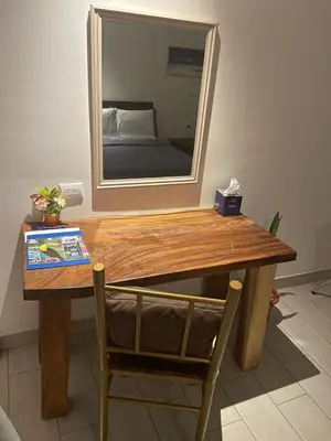 a wooden table with a mirror and a chair at LOP Inn San Jose Aeropuerto - Costa Rica in Ciudad Cariari