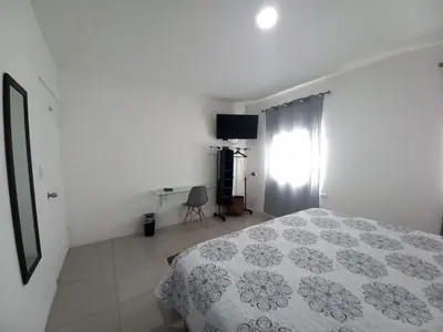 a white bedroom with a bed and a window at W's Hostel in San José