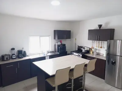 a kitchen with a table and chairs and a refrigerator at W's Hostel in San José