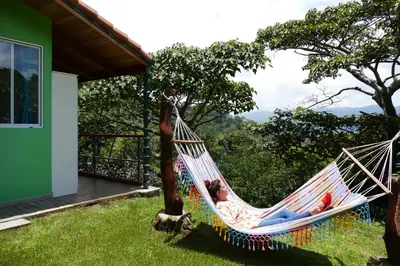 a woman laying in a hammock in a yard at Bungalows Sanlaz in Barrio Jesús