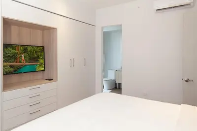 a white bedroom with a bed and a tv at Residencias Cityzen cerca del Aeropuerto in Echeverría