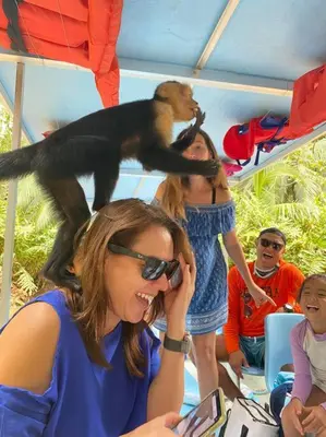 a woman talking on a cell phone with a monkey on her head at Lovely 2-BDroom Condo in Laguna Eco Village Resort in Quepos