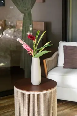 a white vase with flowers on a table in a living room at Hotel Por Qué No in Uvita