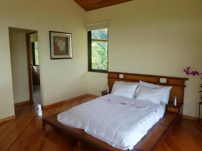 a bedroom with a bed with white sheets and a window at Casa Altamar in Jacó