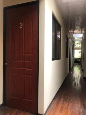 a hallway with a brown door and a hallway with white walls at #2 private room close to airport in Alajuela City