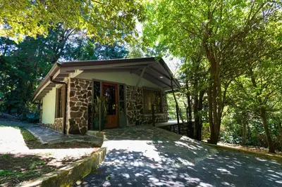 a small stone house with awning and trees at Los Pinos Cabins & Reserve in Monteverde Costa Rica