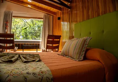 a bedroom with a bed and a large window at Los Pinos Cabins & Reserve in Monteverde Costa Rica