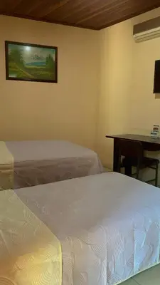 a bedroom with two beds and a desk with a table at Hotel La Guaria in Liberia