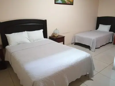 a bedroom with two beds with white sheets at Hotel La Guaria in Liberia