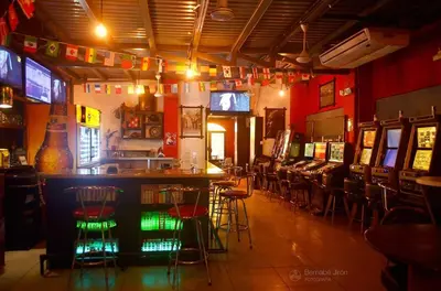 a bar with stools in a room with televisions at Hotel La Guaria in Liberia