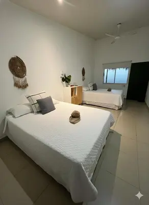 two beds in a room with white walls at Refugio Surf Lodge in Tamarindo