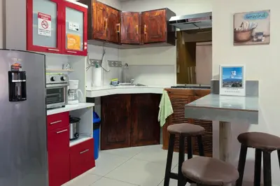 a kitchen with red cabinets and bar stools in it at Nice private apartment studio to discover CR in Alajuela City
