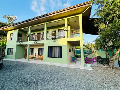 a yellow and green house with a balcony at Hotel La Fiore de Bahia in Uvita