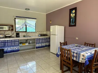 a kitchen with a table and a white refrigerator at Hotel La Fiore de Bahia in Uvita