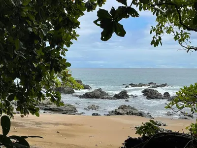 a view of a beach with rocks and the ocean at Hotel La Fiore de Bahia in Uvita