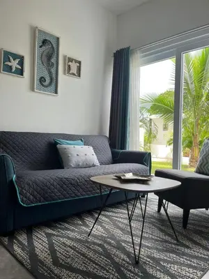 a living room with a blue couch and a table at Lapa Lodge G1 in Jacó
