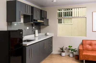 a kitchen with black cabinets and a orange chair at Otoya 1907 Hotel in San José