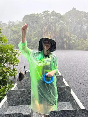 a woman in a raincoat standing on steps in the rain at Hotel Serendipity in Tortuguero