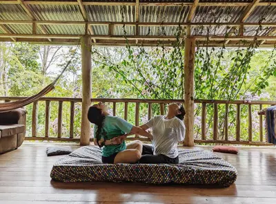 two people sitting on a bed in a room at Centro Ecológico Montaña Verde in Rivas