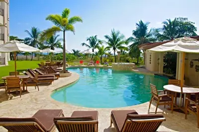 a pool at a resort with chairs and tables at Beach Front Boutique Condominium in Jacó