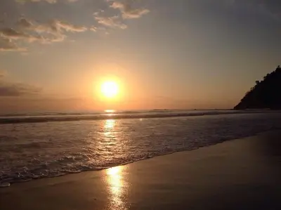 a sunset on a beach with the ocean at Beach Front Boutique Condominium in Jacó