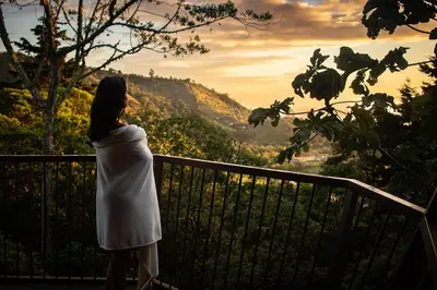 a woman standing on a balcony looking at the sunset at Casa Tucan Glamping in Turrialba