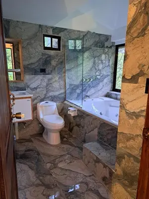 a stone bathroom with a toilet and a tub at Casa Tucan Glamping in Turrialba