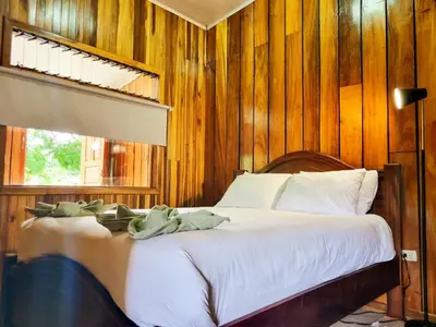 a bedroom with a bed with wooden walls and a window at CASA ISAMAR in Monteverde Costa Rica
