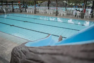 an empty swimming pool with tables and chairs at Hotel Suerre in Guápiles