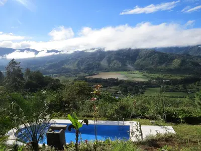 a view from the hillside of a swimming pool and a mountain at El Ensueño in Ujarrás