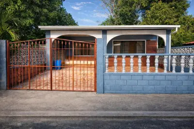 a fence with an orange gate in front of a house at Cabinas Miramar, una casa SOLO para ti in San Isidro