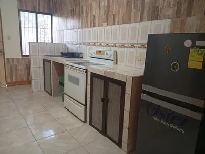 a kitchen with a stove and a refrigerator at Cabinas Miramar, una casa SOLO para ti in San Isidro