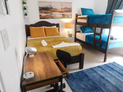 a bedroom with a bed and a desk and bunk beds at Sunset 205, sleeps six, next door to the pool, 100m to the beach! in Jacó