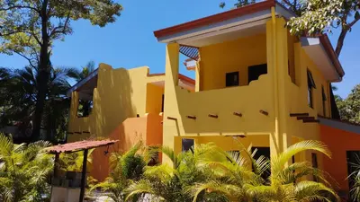 a yellow house with palm trees in front of it at Hotel Tabasco in Playa Flamingo