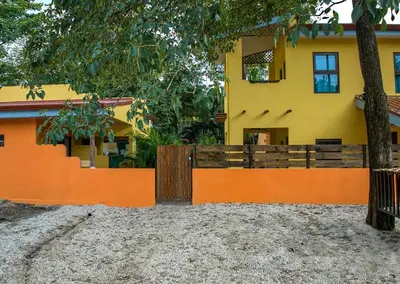 a house with an orange fence and a tree at Hotel Tabasco in Playa Flamingo