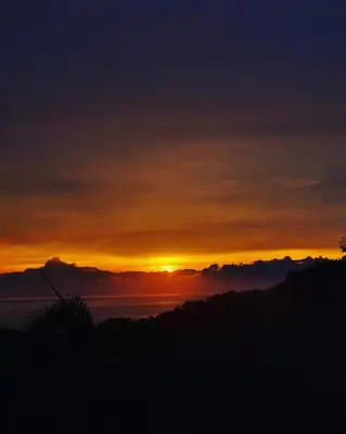 a sunset with the sun setting over the ocean at Ballena Oasis Homes( Dep Estudio con AC) in Uvita