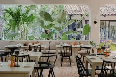 a restaurant with tables and chairs and plants at Sendero Hotel in Nosara