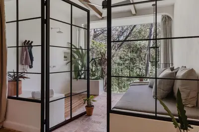a bedroom with glass walls and a bed with a window at Sendero Hotel in Nosara