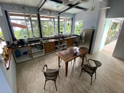 a kitchen with a table and chairs and a refrigerator at Jungle Villa copa de árbol, oceanview, infinity in Montezuma