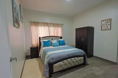 a bedroom with a large bed with blue pillows at Casa en puntaleona Condomio Bambu in Quebrada Ganado