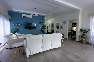 a living room with white furniture and a blue wall at Casa en puntaleona Condomio Bambu in Quebrada Ganado