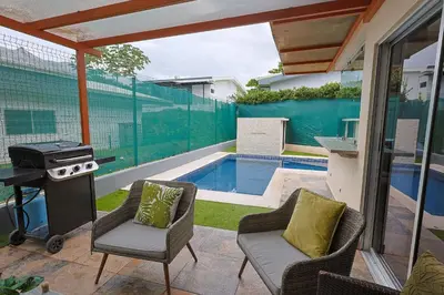 a backyard with a grill and chairs and a swimming pool at Casa en puntaleona Condomio Bambu in Quebrada Ganado