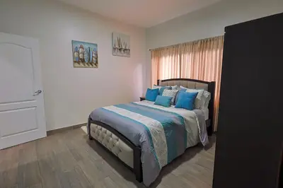 a bedroom with a bed with blue pillows and a window at Casa en puntaleona Condomio Bambu in Quebrada Ganado