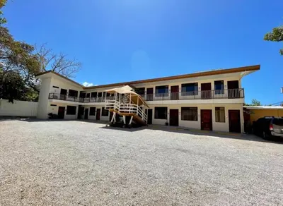 a large white building with a balcony and a parking lot at Hotel Wilson Condega in Liberia