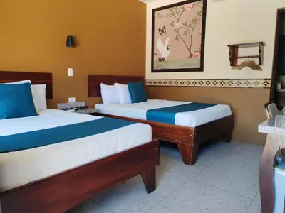 a hotel room with two beds with blue and white sheets at Hotel Wilson Condega in Liberia