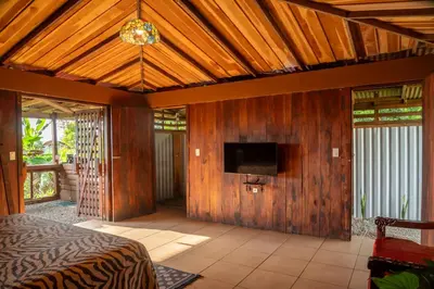 a bedroom with a bed and a tv on a wooden wall at Terraé Eco-Sanctuary in Santa Elena