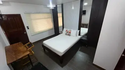 a small room with a bed and a chair at Hotel Wilson Anexo in Liberia